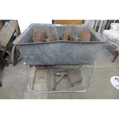 341 - A galvanised trough on stand and agricultural tool implements