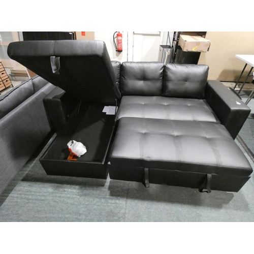 3083 - A black upholstered L-shaped sofa with pull-out bed and lift up ottoman storage * this lot is subjec... 