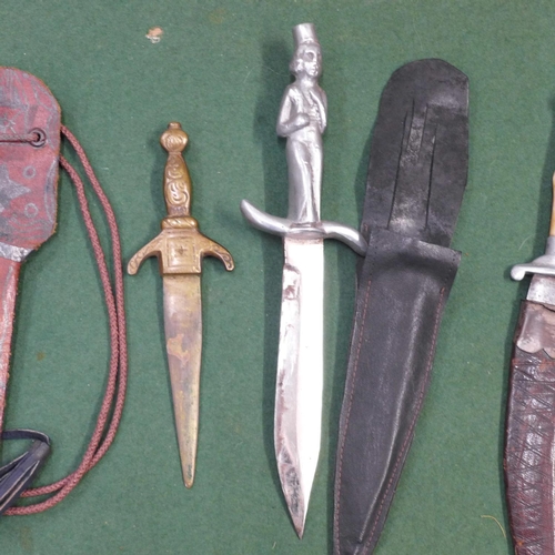 734 - Three daggers; one figural handle, one curved blade and one small brass