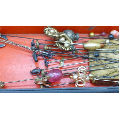 749 - A collection of hat pins in a lacquered glove box