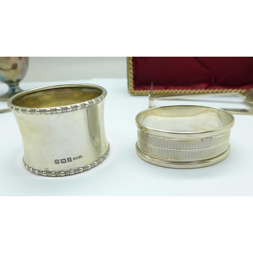 1043 - Two silver napkin rings, a silver feeding spoon and pusher and a silver egg cup and spoon, 110g, den... 