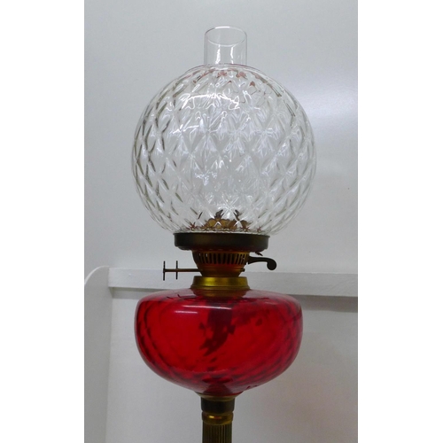 897 - A brass oil lamp with red glass reservoir