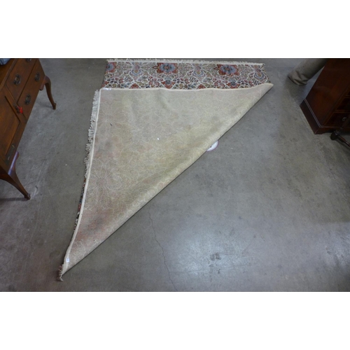 310 - A large beige and red floral ground rug