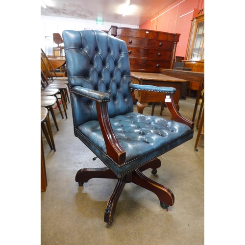 105 - A mahogany and blue buttoned leather revolving desk chair