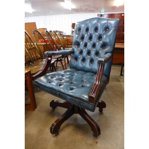 105 - A mahogany and blue buttoned leather revolving desk chair