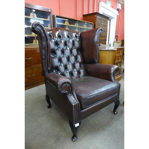 111 - A brown leather Chesterfield wingback armchair