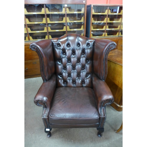 111 - A brown leather Chesterfield wingback armchair