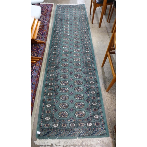 93 - A Pakistani hand knotted Bokhara green groung runner rug, 320 x 81cms