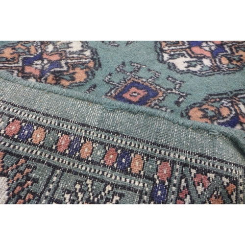 93 - A Pakistani hand knotted Bokhara green groung runner rug, 320 x 81cms