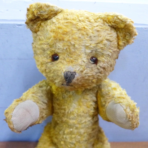 779 - A straw filled jointed Teddy bear in orange plush, material pads with glass eyes, 14½