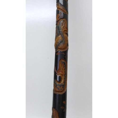 840 - A Japanese ebonised bamboo walking cane, root finial, with finely carved decoration of two snakes, a... 