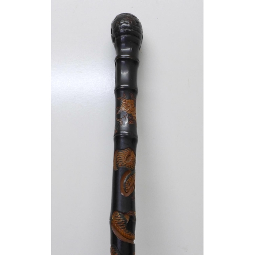 840 - A Japanese ebonised bamboo walking cane, root finial, with finely carved decoration of two snakes, a... 