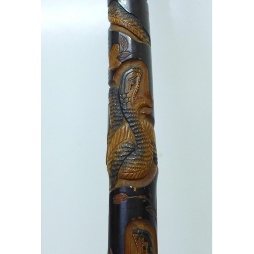 840 - A Japanese ebonised bamboo walking cane, root finial, with finely carved decoration of two snakes, a... 