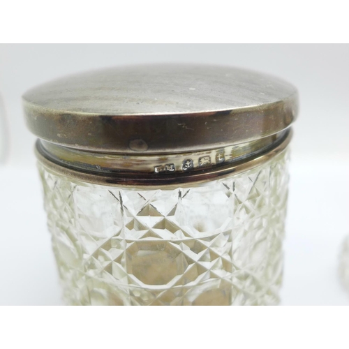 851 - Three silver topped glass scent bottles and a silver topped glass jar