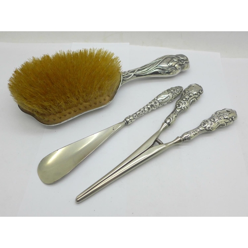 854 - An Art Nouveau silver backed hair brush, silver handled glove stretchers and a similar shoe horn