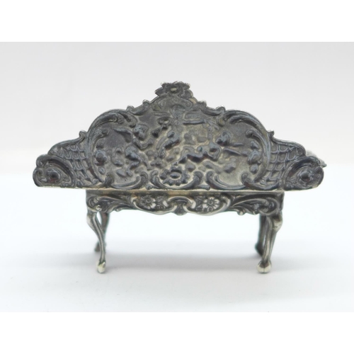 900 - A hallmarked silver dolls house settee with embossed cherubs, London mark, 17g, 62mm wide