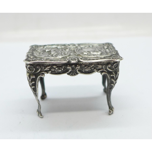 901 - A hallmarked silver dolls house table with embossed cherubs, London mark, 14g, 43mm wide