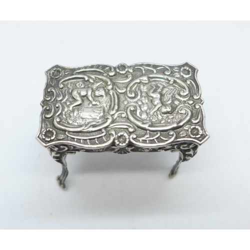 901 - A hallmarked silver dolls house table with embossed cherubs, London mark, 14g, 43mm wide