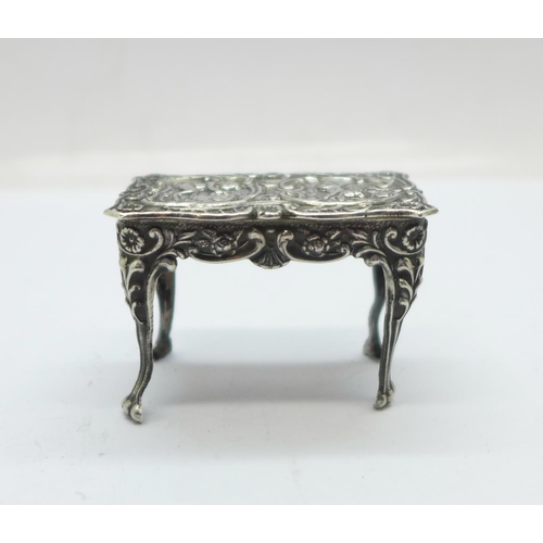 901 - A hallmarked silver dolls house table with embossed cherubs, London mark, 14g, 43mm wide