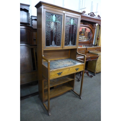 93 - An Arts and Crafts oak and stained glass two door writing cabinet