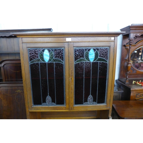 93 - An Arts and Crafts oak and stained glass two door writing cabinet