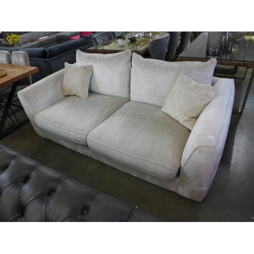 1323 - A cream upholstered three seater sofa