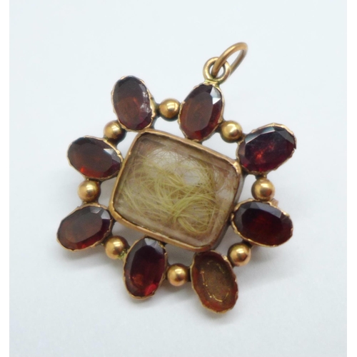 1037 - A rolled gold and garnet mourning pendant/brooch, lacking one stone