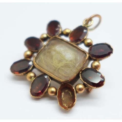 1037 - A rolled gold and garnet mourning pendant/brooch, lacking one stone