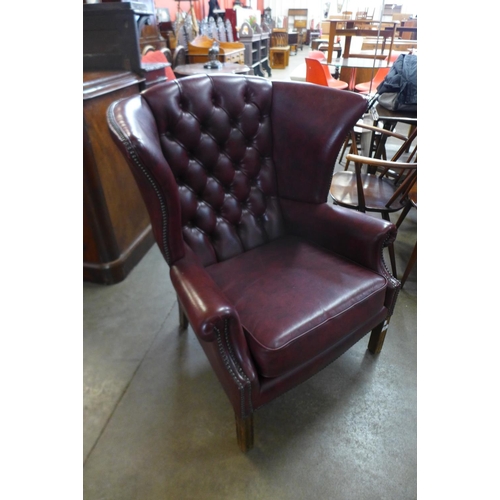 63 - A burgundy faux leather wingback armchair