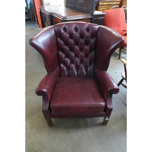 63 - A burgundy faux leather wingback armchair