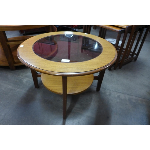 76 - A teak and glass topped circular coffee table