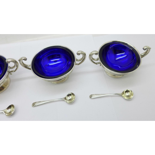 850 - A set of four silver salts with blue glass liners, Birmingham 1907, the spoons hallmarked London 190... 