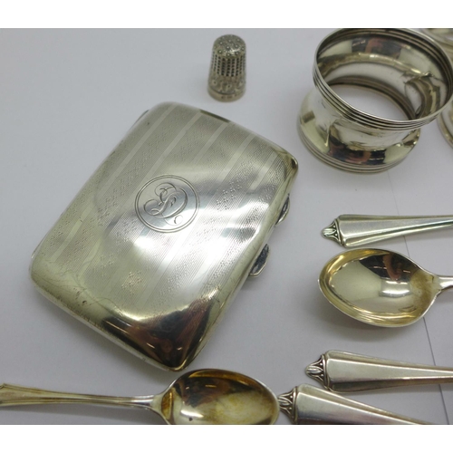 857 - A silver cigarette case, four silver napkin rings, eleven silver spoons, two plated spoons and a sil... 