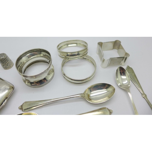 857 - A silver cigarette case, four silver napkin rings, eleven silver spoons, two plated spoons and a sil... 