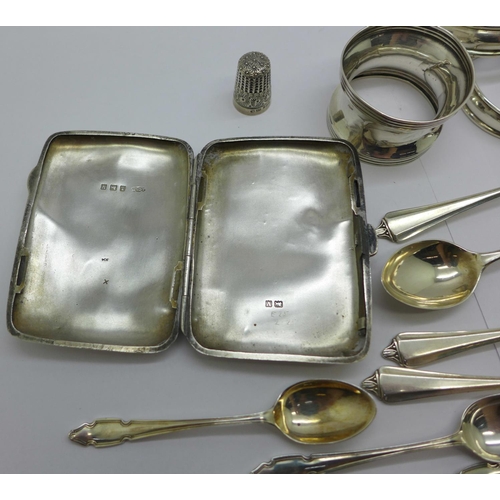 857 - A silver cigarette case, four silver napkin rings, eleven silver spoons, two plated spoons and a sil... 