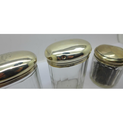 887 - Three silver topped glass jars including one Victorian, 64g of silver, tops dented