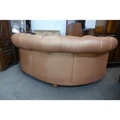 100 - A buttoned faux leather copper coloured demi lune settee