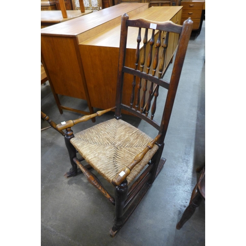 85 - A George III elm rush seated spindle back rocking chair