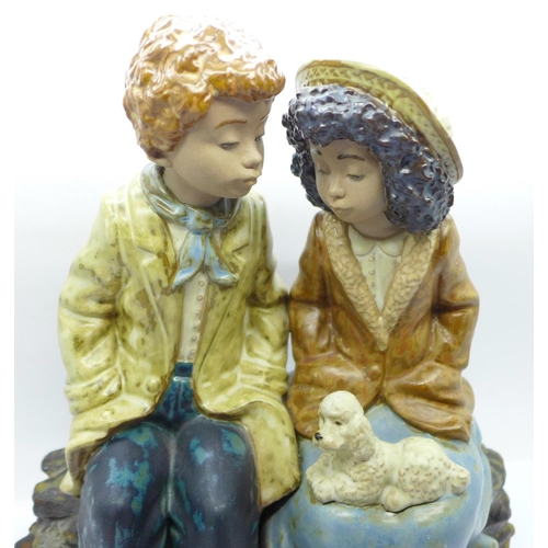 601 - Nao by Lladro, a large figurine of a boy and girl sitting on a log, E-2S backstamp, 25.5cm