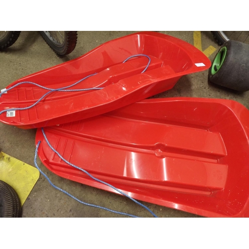 2458 - 2 Red plastic sledges - unused