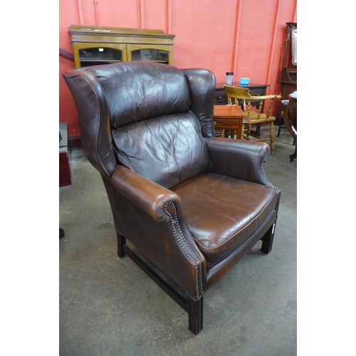 16 - A mahogany and studded chestnut brown leather wingback armchair