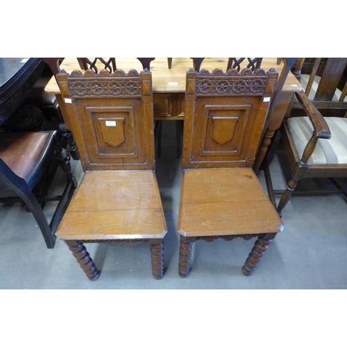 150 - A pair of Victorian Gothic Revival oak hall chairs