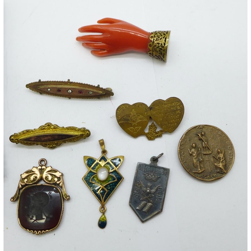 1033 - A carved hand brooch, three other brooches, a fob, a pendant marked 950MB, a/f, and three medallions