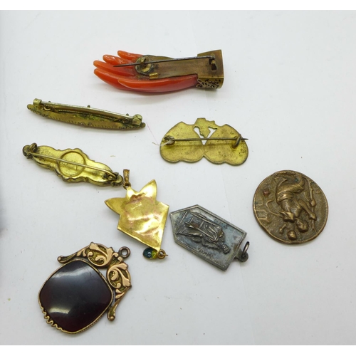 1033 - A carved hand brooch, three other brooches, a fob, a pendant marked 950MB, a/f, and three medallions