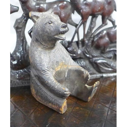 745 - A Black Forest carved seated bear and three carved shelves