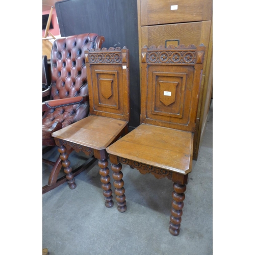 150 - A pair of Victorian Gothic Revival oak hall chairs