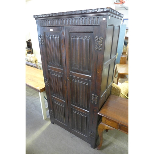 210 - A carved oak linenfold panel wardrobe