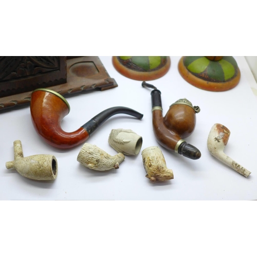 689 - A Black Forest carved pipe stand tobacco box, two pipes and clay pipe bowls and a pair of painted wo... 