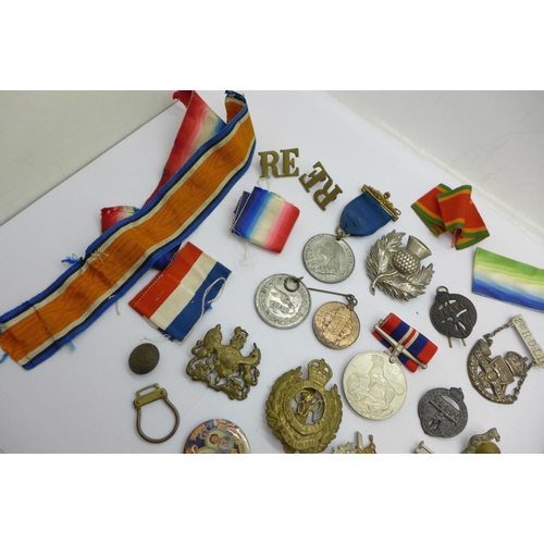 880 - A collection of military badges, medallions, medal ribbons, etc.