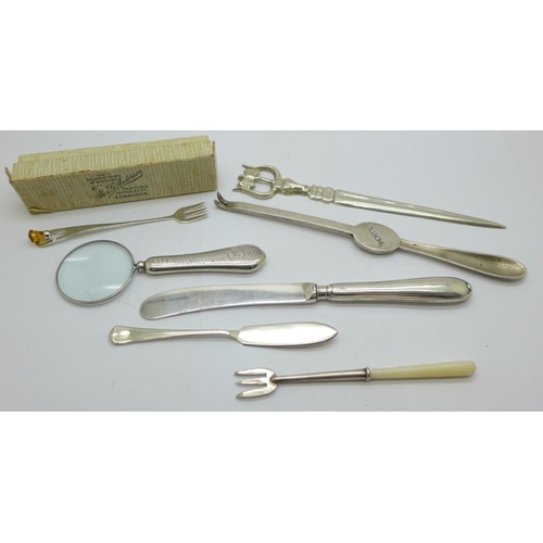 923 - A silver handled magnifying glass, two silver forks, a silver butter spreader, a letter opener, etc.